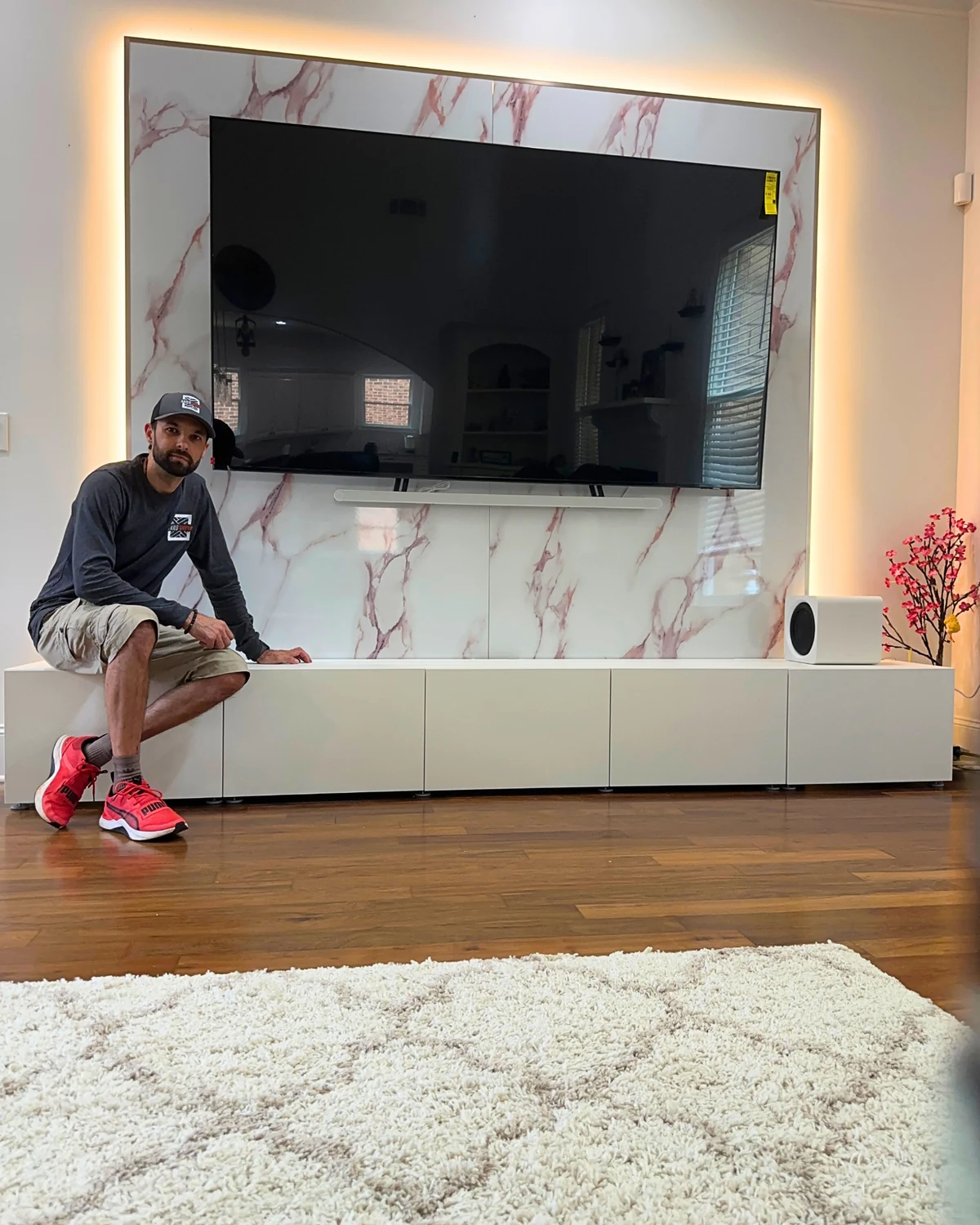 Roman beside a completed backlit marble-look TV feature wall with white console