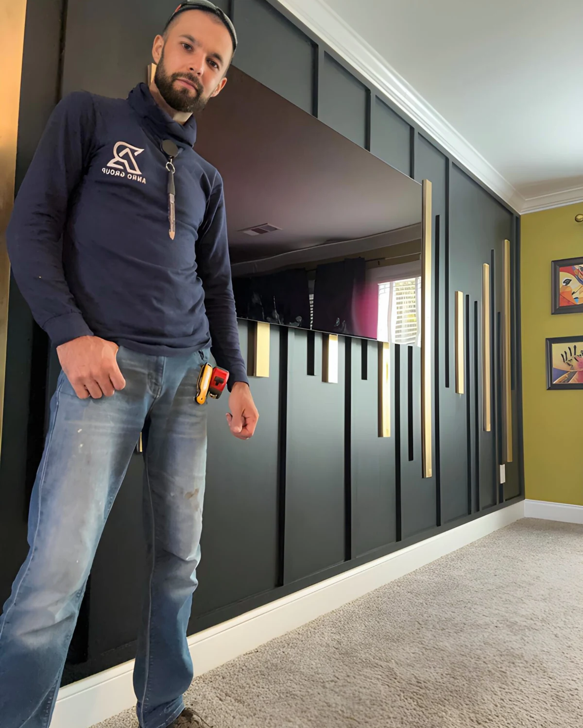 Roman beside a completed black geometric TV accent wall with natural wood accent strips